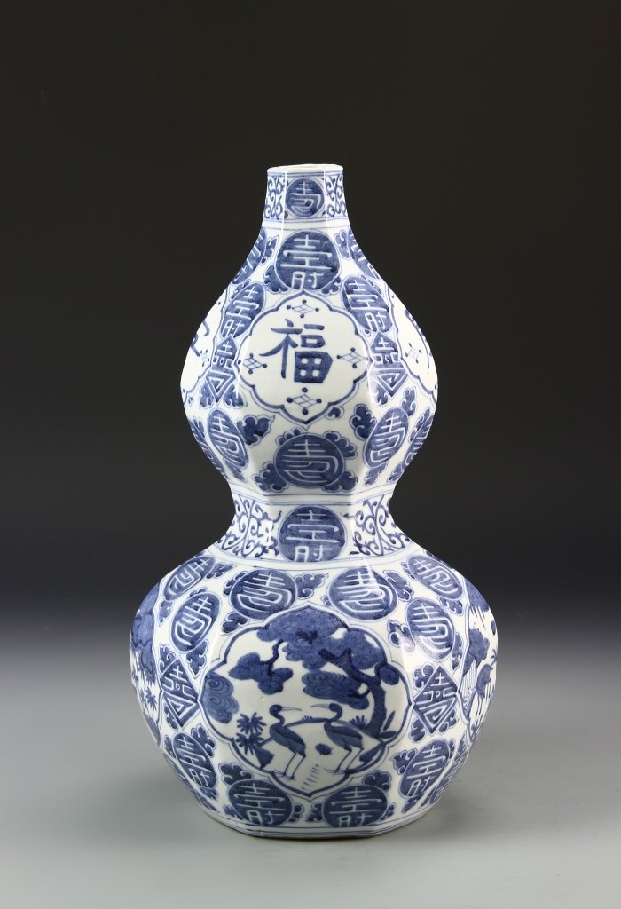 Chinese Antique Blue and White Gourd Vase: China, antique, blue and white gourd vase, double gourd body with hexagonal sides, decorated with auspicious symbols throughout and a stork emblem in blue tones against white ground. Height 16 in.