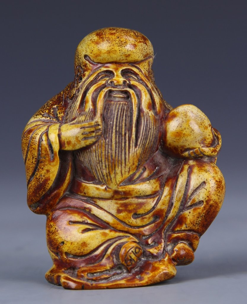 Chinese Carved Shoulao Figure: China, 19th C., carved deer antler Shoulao, in seated position, carrying a gourd in one hand and stroking his beard with the other. Height 3 in.