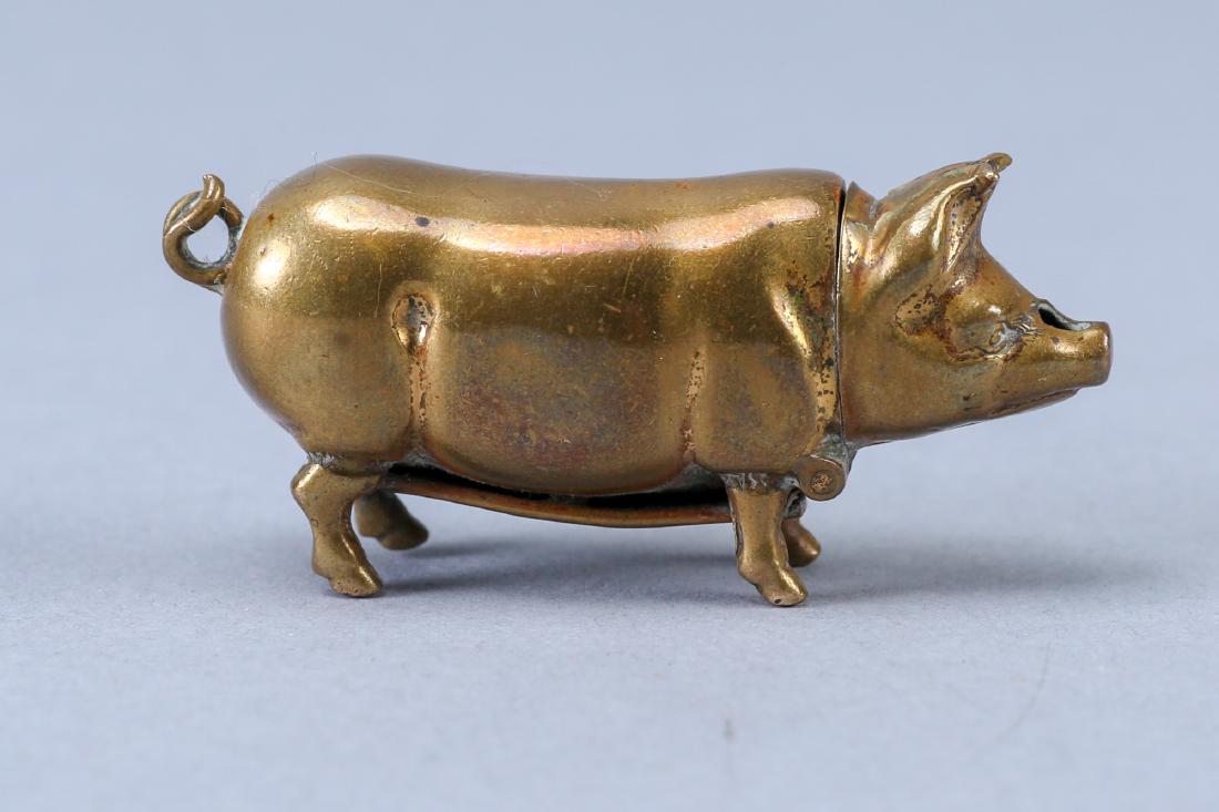 19th Century Brass Pig Match Safe: Adorable little pig match safe with striker on the stomach. Pig is unmarked, has a hole in his snout and his tail acts as a jump ring for a chain. Measures approx 2" x 1".
