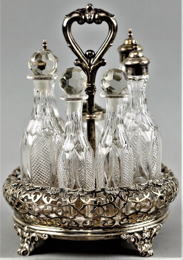 1852 London Sterling Cruet by John Evans II Victorian: Remarkable Victorian sterling cruet service with cut crystal bottles. The heart shaped handle flows into varying shaped arches to accommodate the bottles. The base has lovely reticulated scroll work w