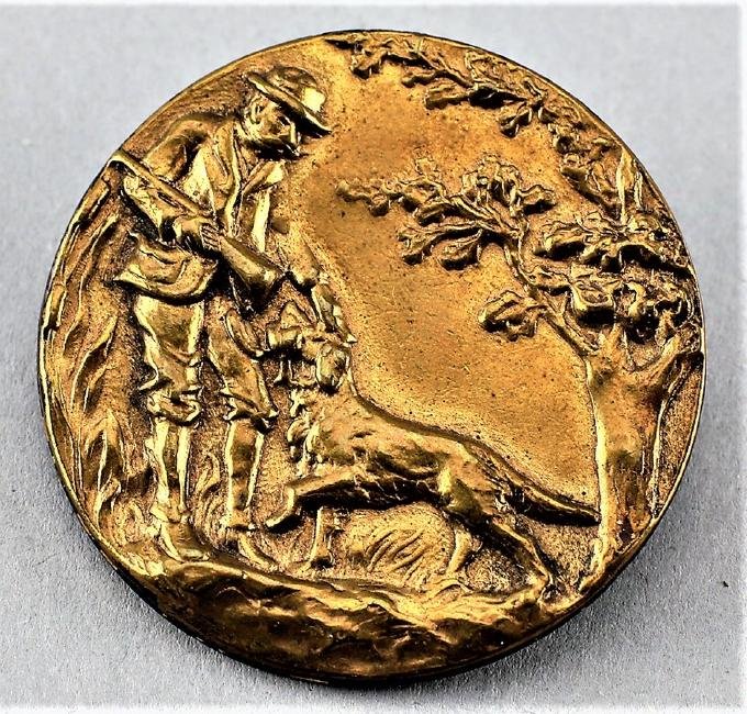 Large Antique Man With Retriever Brass Button: Beautiful detail is highlighted in this large button in brass. The scene is a man cradling a shotgun while the retriever is giving him what appears to be a duck. This single piece of brass appears to 
