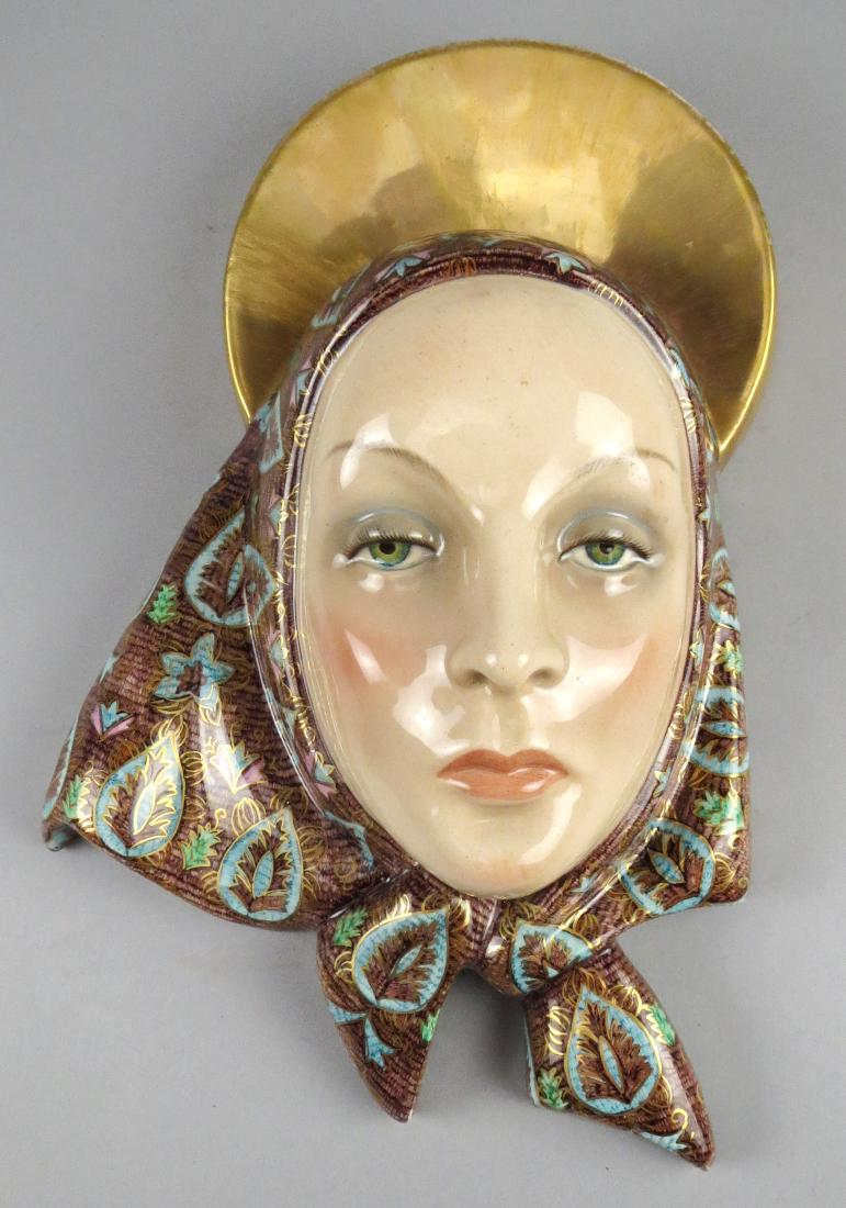 1936 Porcelain Lenci Torino Mask: Lovely porcelain wall hanging mask of a woman, possibly Madonna with a gold halo/crown and blue and brown head scarf. She is hand signed on the back with the artist initials LV. Many of these examples