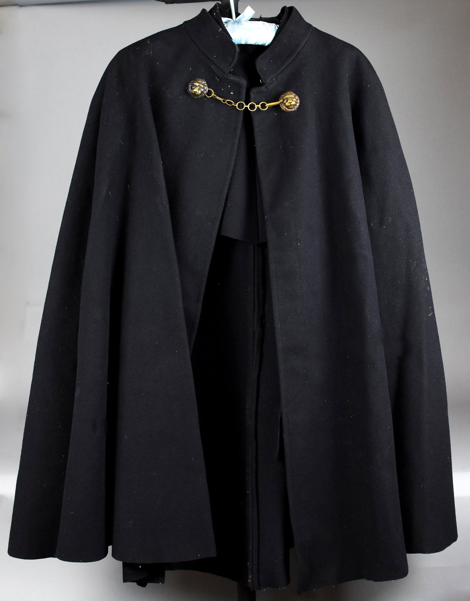 Antique Obsolete British Police Officer: This is a wonderful antique cloak made for the British police. It is very heavy wool with a brass chain and hook closure. Each end of the chain is attached to a lion head sewn into the fabric. Remains