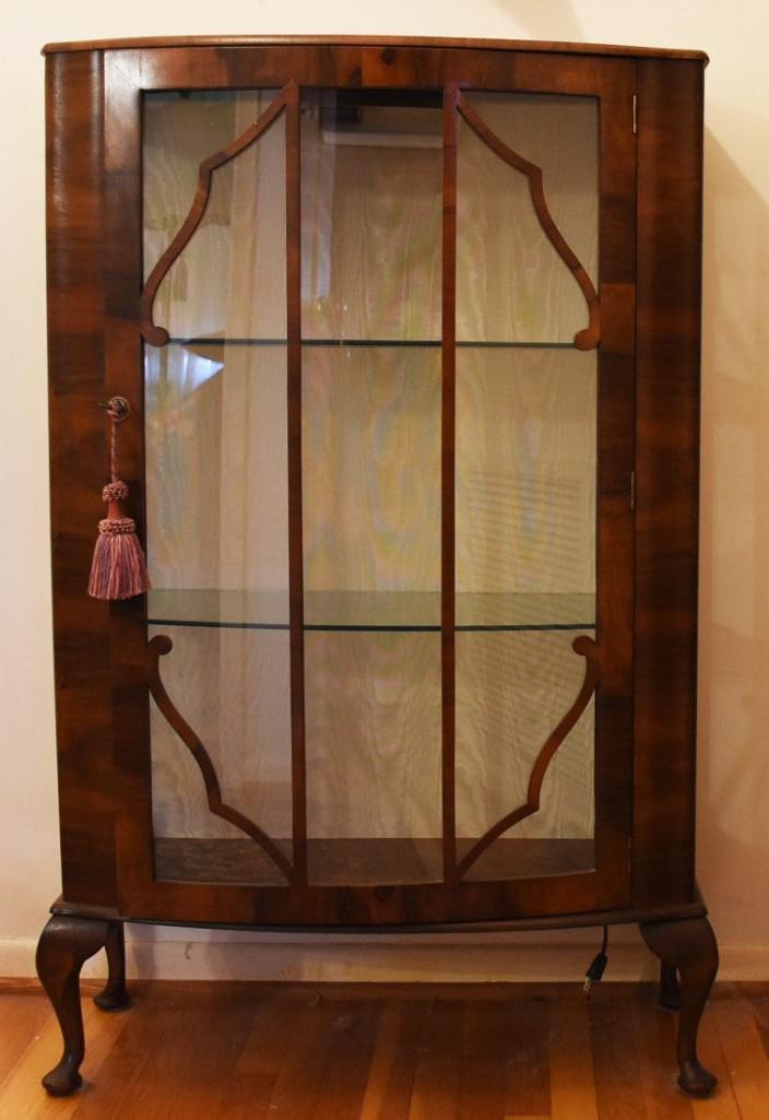 Art Deco Curved Front Display Cabinet: Description This pretty Art Deco veneer cabinet will hold a good amount of your antiques and collectibles. The back wall is off white moire fabric. The client added a light and attached the cabinet to