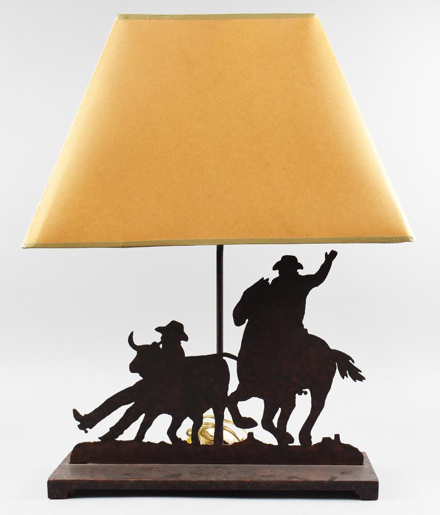 Metal Cowboy Rodeo Silhouette Table Lamp: Very cool table lamp in a rodeo theme. The die cut metal is a silhouette of a horse and rider along with a cowboy wrangling a steer. Silhouette is attached to a cast metal base. Measures approx 24,5&#