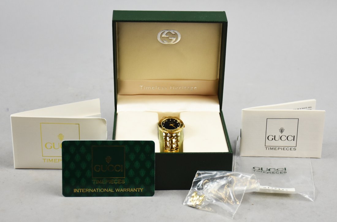 Gucci 3000.2.L Black and Gold Wristwatch: Wonderful Gucci gold plate wristwatch with a fixed Roman numeral dial and black enamel face. Lots out there with leather bands, harder to find with the original gold plate stainless band stamped with