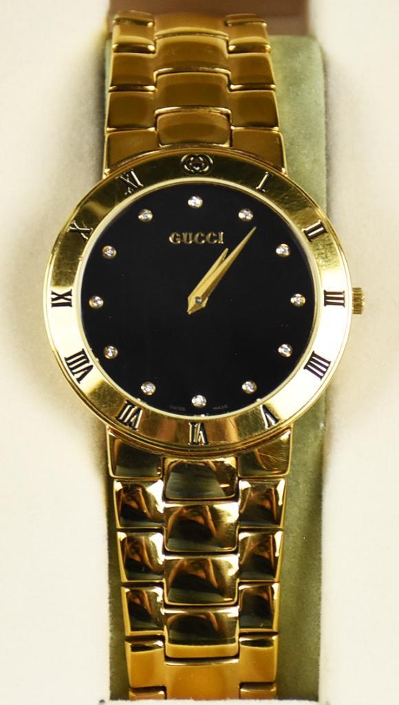Gucci 3300.2.M Black and Gold Wristwatch: Nice gentlemen's Gucci 3300.2.M black and gold wristwatch. Fixed Roman numeral dial with black face. Comes with original gold plate stainless band with the GG logo. Has original presentation box a