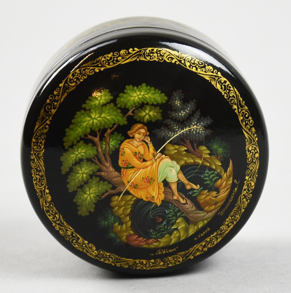 Russian Fairy Tail Lacquer Trinket Box, w/ COA: This beautiful lacquer box is believed to be a depiction of a fairy tale. Woman is sitting on a tree with what looks to be a fishing rod. Box is hand painted and signed and includes a COA. Measures 2.