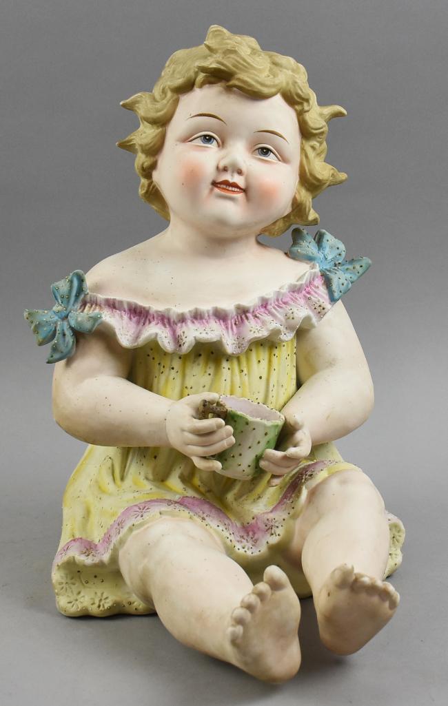Antique Conta & Boehme Painted Piano Baby w/ Cup: This wonderful bisque piano baby is hand painted. Conta & Boehme girl holding a cup. She has sculpted blond hair with pail yellow dress with blue bows on shoulders. Unmarked and stands approx 14" tall