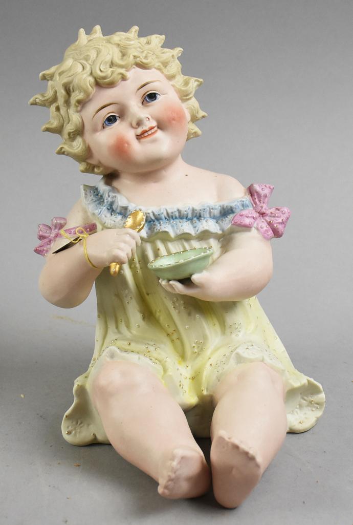 Antique Conta & Boehme Painted Piano Baby w/ Bowl & Spoon: Darling piano baby from Conta & Boehme of the little girl with molded curly hair and hand painted features. She holds a gold gilt spoon in one hand and bowl in the other. Light painted yellow dress wi
