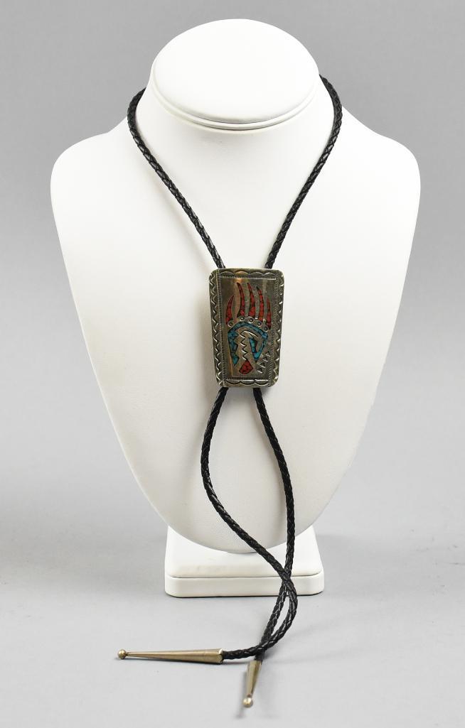 Vintage Navajo Signed Turquoise and Coral Claw Bolo: Terrific bolo tie of Navajo origin. The bear claw is inlaid with turquoise and coral and is sterling. The mark on the ornamental clasp is, SW or WS, possibly for Willie Shaw. Sterling tips on braided 