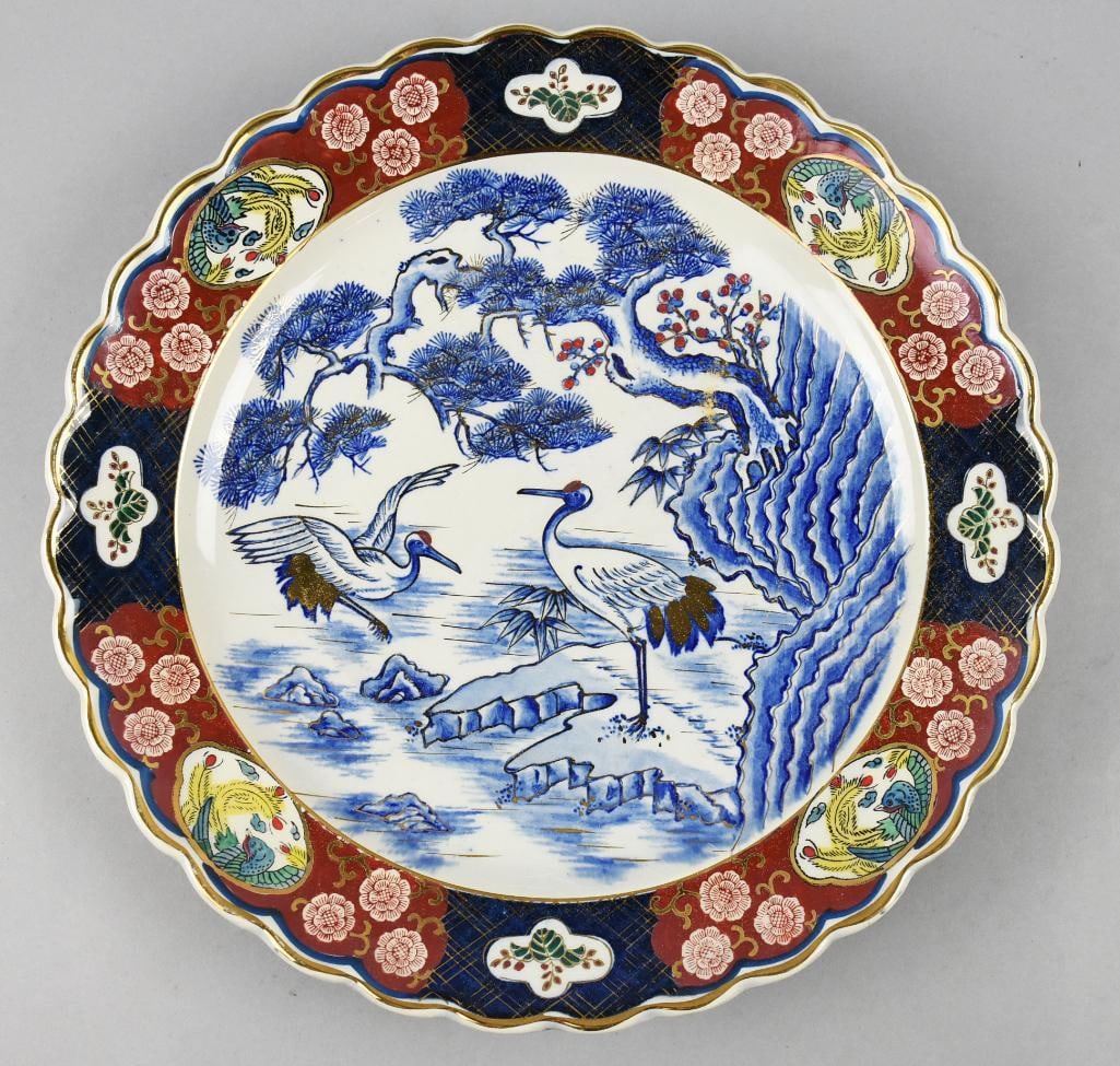 Vintage Japanese Cranes Porcelain Charger: Wonderful mid century Japanese porcelain charger. Blue and white with iron red accent colors and appears hand painted with cranes in a landscape and floral scalloped rim. Retains original paper label,