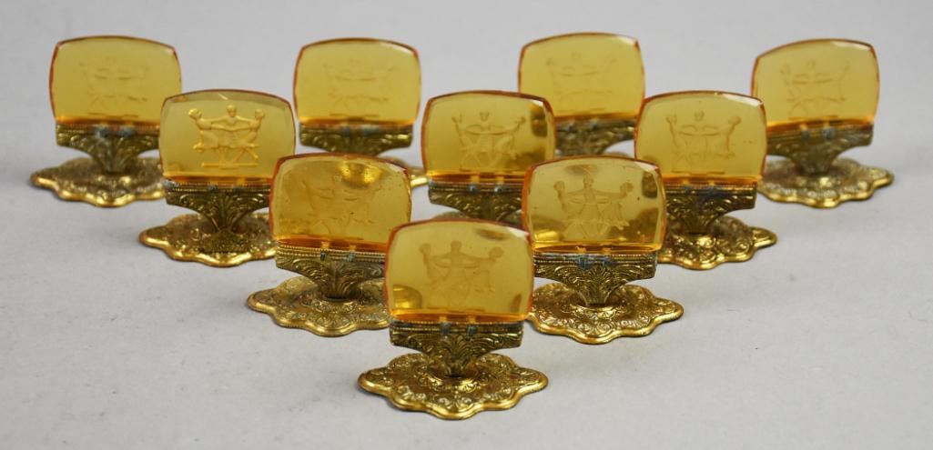 (10) Vintage Czech Intaglio Glass Place Holders Art Deco: Beautiful Art Deco bohemian Czech glass place holders. Each is intaglio amber glass with dancing girls all in what appear to be brass bases with heavy gold gilting. All approx. 2" x 2".