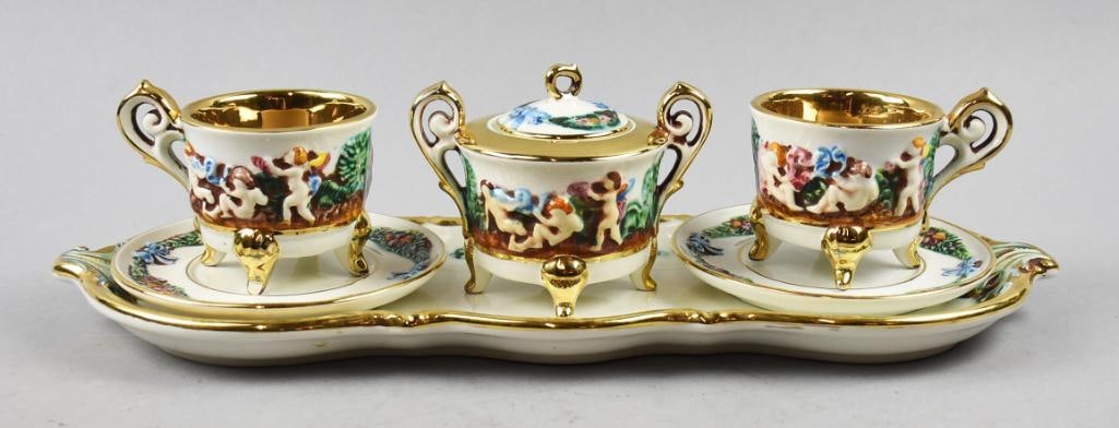 Vintage R. Capodimonte Porcelain Putti Tea/Coffee Set: This fantastic set is R. Capodimonte. Set is porcelain with raised Putti and foliage, appearing hand painted. Four footed cups that are heavy gold gilt on foot, legs and inside, all pieces with gold a