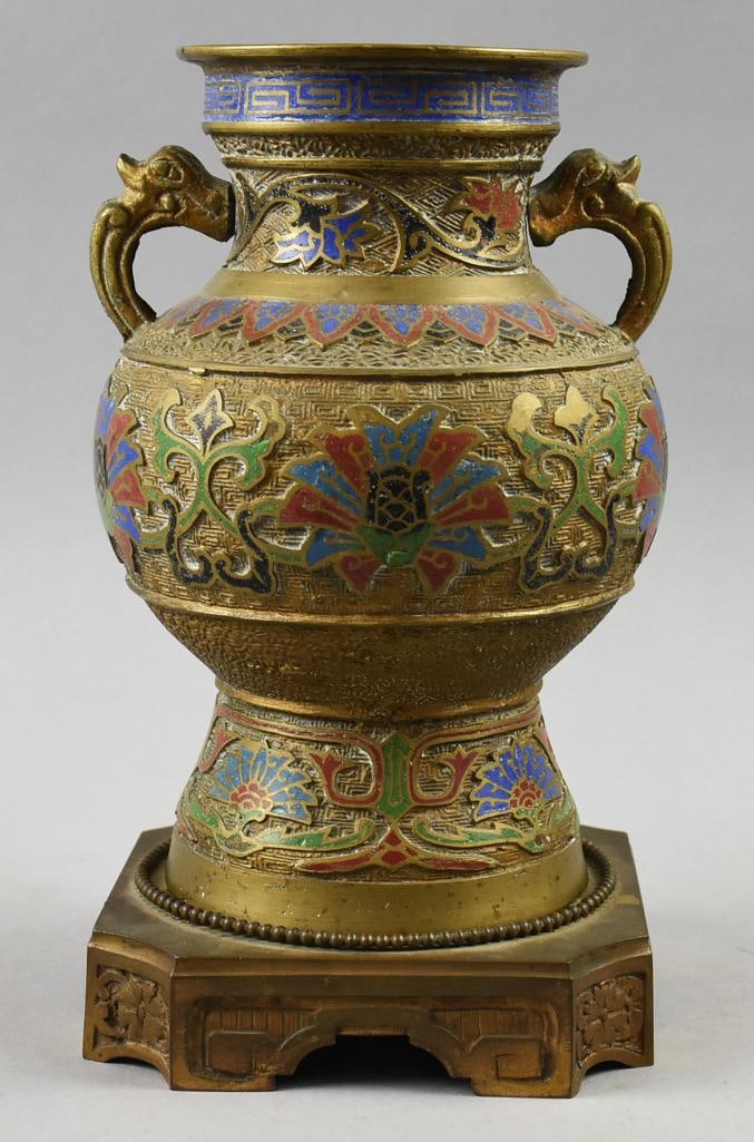 Chinese Brass Champleve Cloisonne Urn Vase on Stand: Very pretty piece of vintage Chinese brass. Shape is a vase incised throughout and champleve in red, blue, green and black and figural handles. Floral motif throughout, meander around neck with rich b