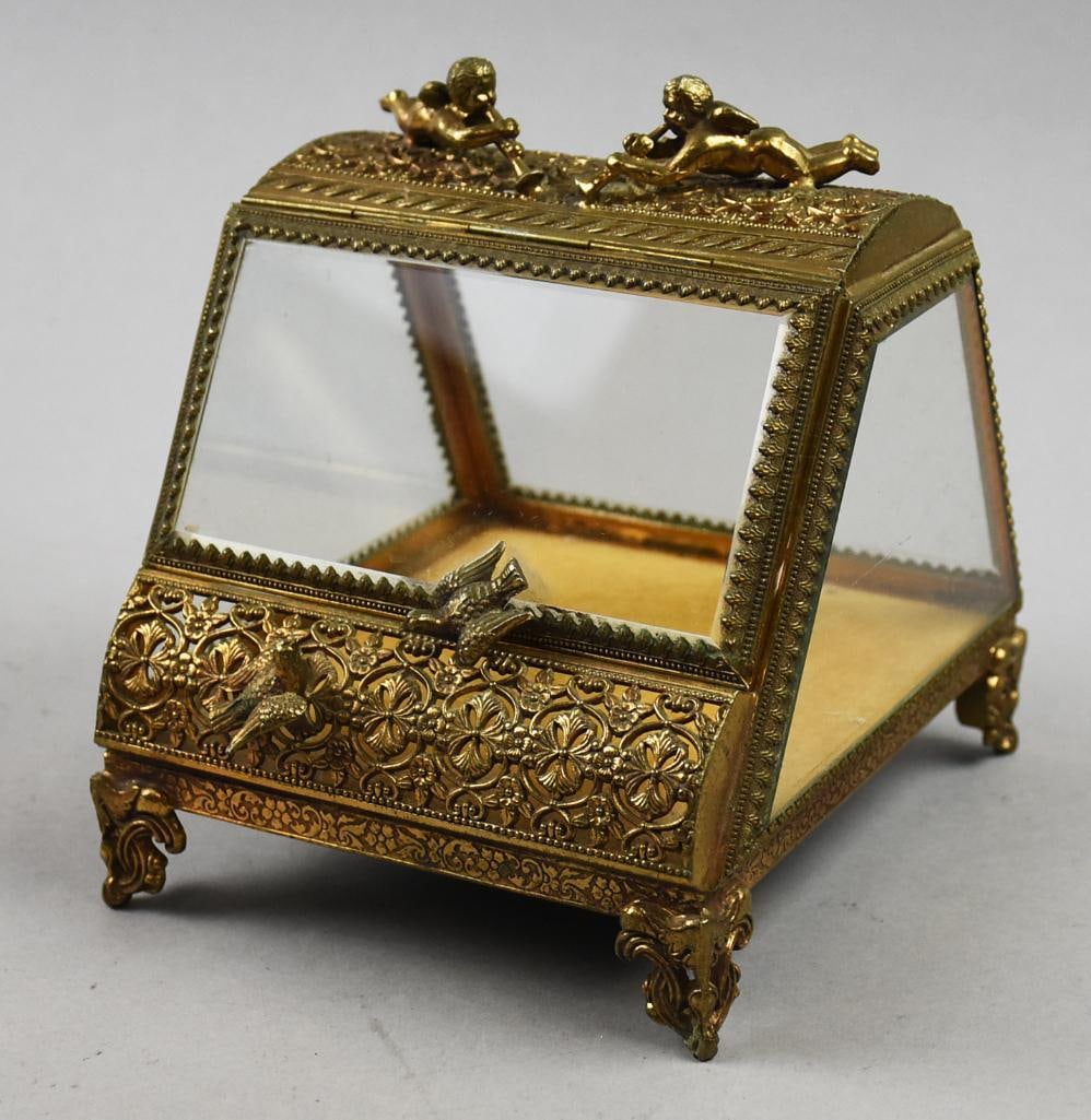 Antique French Putti & Dove Ormolu Jewelry Casket: This gorgeous ormolu jewelry casket is of French origin. It is an unusual shape with subtle dome top with applied Putti. Beveled glass door front lifts upwards with one of the two doves as a handle. G