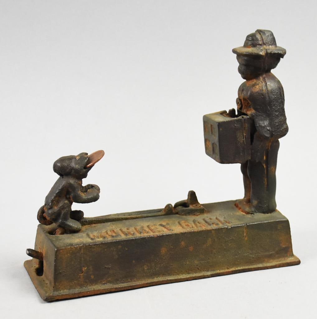 Cast Iron Monkey Bank,\: Fun reproduction bank in cast iron. It is called Monkey Bank originally produced by Hubley. Place coin in monkey's mouth, press the lever and the monkey drops the coin in the hurdy gurdy the man is ho