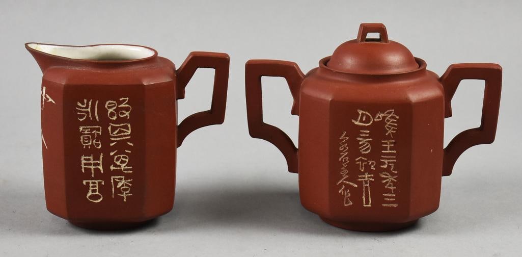 c1970 Chinese Yixing Zisha w/ Calligraphy Creamer/Sugar Bowl: Beautiful vintage red clay pottery made in China. Both the cream pitcher and sugar bowl with lid have calligraphy and what appear to be bamboo engraved in each. Bottoms are impressed marked, not fully