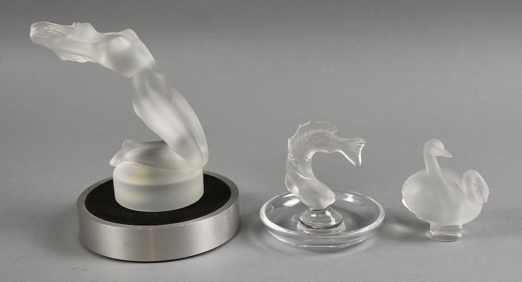 Lalique Paperweight Assorted Art Crystal Pieces: Very pretty selection of art crystal from Lalique. Lot includes a nude female mascot known as Chrysis, Koi fish ring dish and a double swan paperweight. Each measure from 3" to 6" tall.
