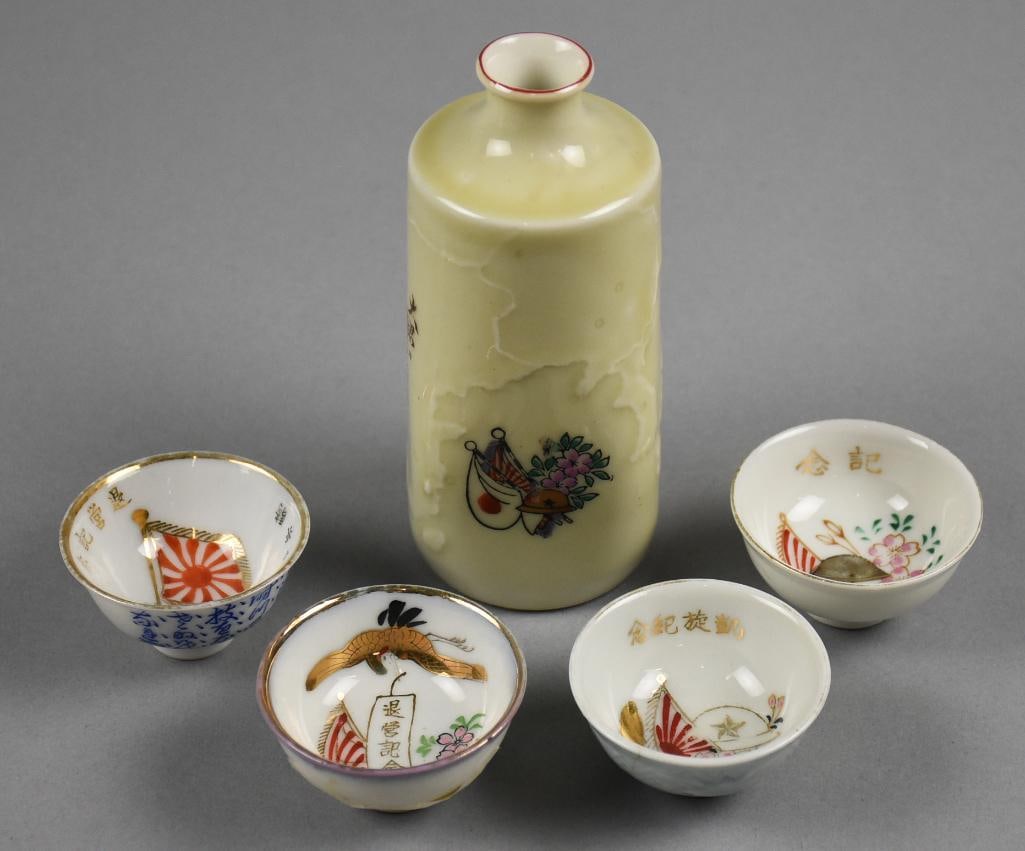 WWII Era Japanese Porcelain Military Sake Bottle & Cups: Great collection of Japanese military cups and sake bottle from the WWII era. Bottle is embossed with hand painted helmet, flag and flowers with calligraphy. Cups all with slightly varying designs inc