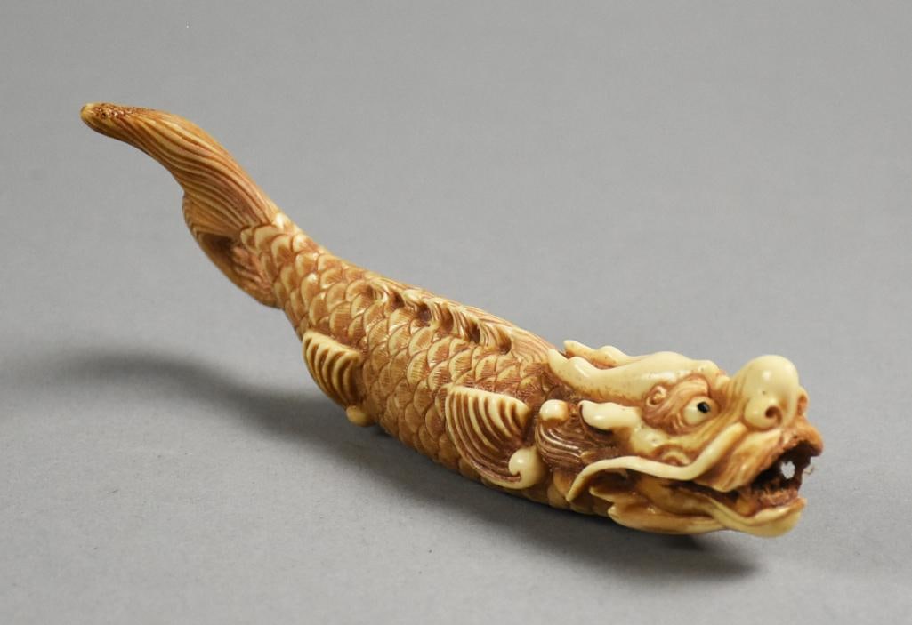 Japanese Carved Bone Dragon Fish Netsuke, Signed: This is a great antique bone netsuke. Hand carved dragon fish with long whiskers, detailed scales and looped tail. It is signed near the two holes on the belly, measures approx. 5" long x 3" tall.