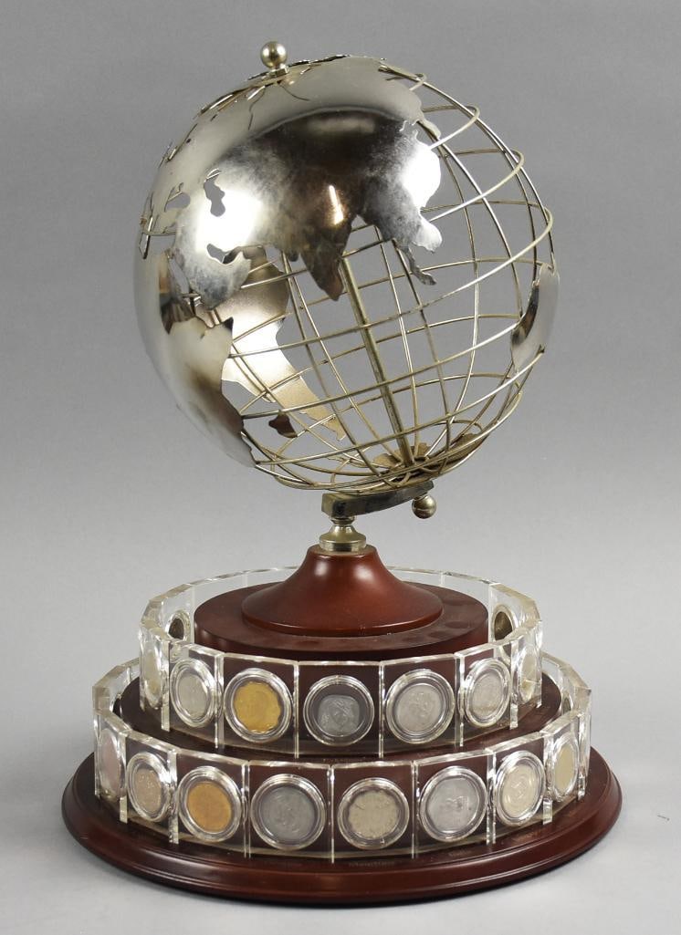 Danbury Mint Globe Sculpture & 36 Clad World Coins: Lot is a Danbury Mint Globe Sculpture & 36 World Coins on a rotating base. Metal globe with coins from around the world, all encased. Coins appear clad. Years include: 1974, 1978-1980, 1982-1985, 1987