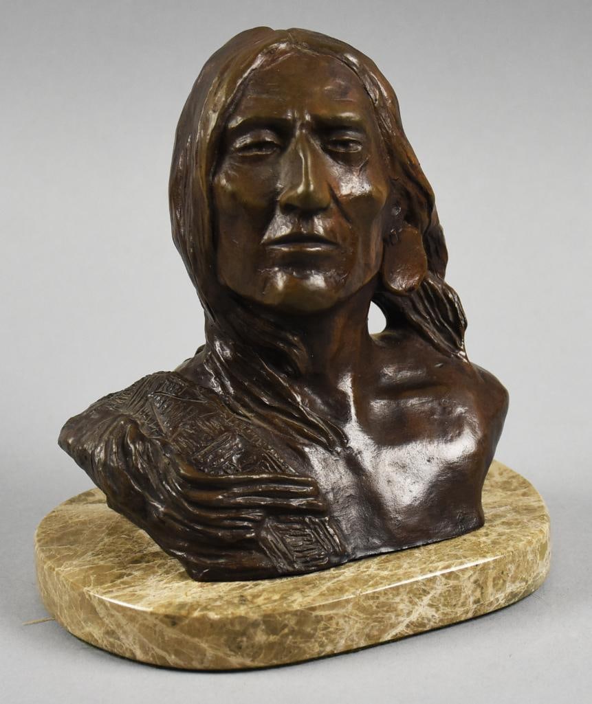 After Charles M Russell (1864-1926) Native American Bronze: Great bronze bust of a Native American and is after Charles Marion Russell (1864-1926). He is looking slightly upwards with long hair and a blanket over one shoulder. Artist name in on the back right 