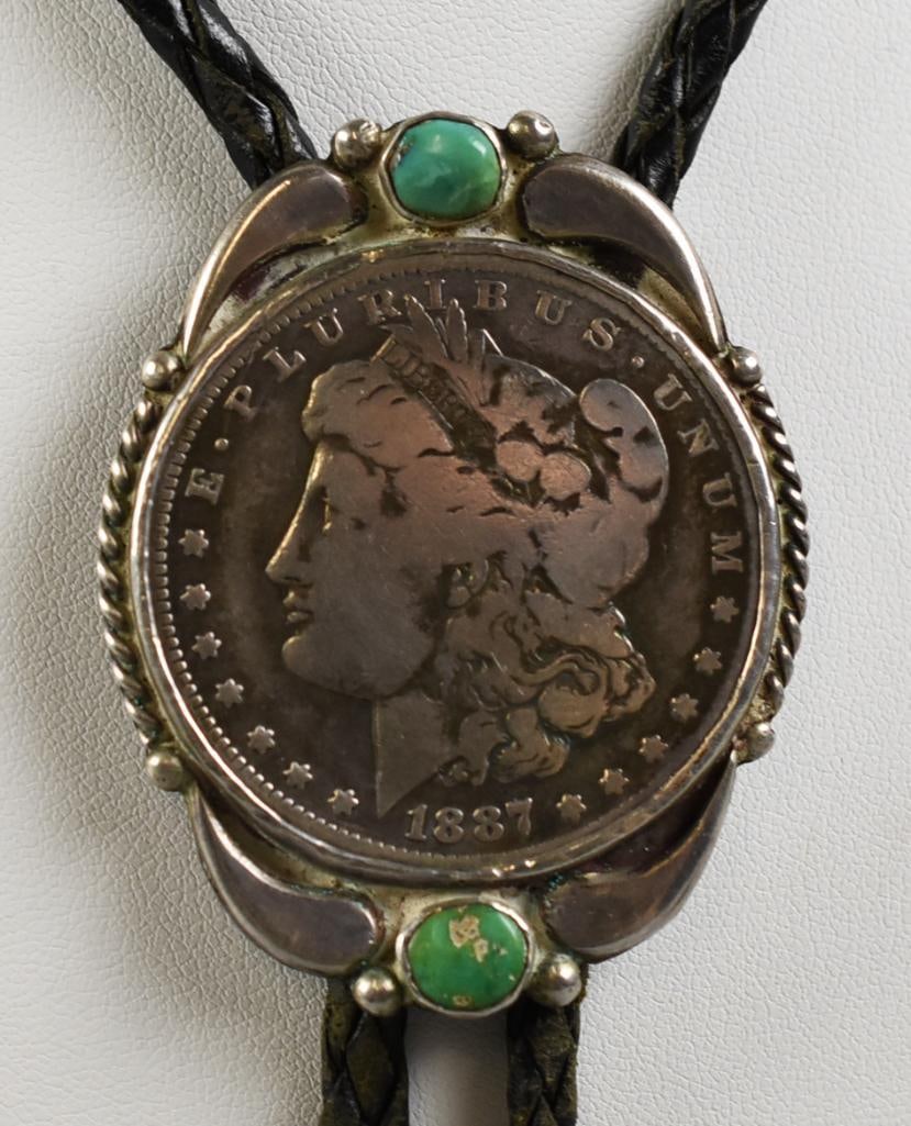 Allen Pooyouma Turquoise, Sterling Morgan Silver Dollar Bolo: This really cool bolo tie is from Hopi jewelry artist Allen Pooyouma. Sterling setting with green turquoise stones and an 1887 Morgan silver dollar. Leather rope has silver end caps with squash bead o