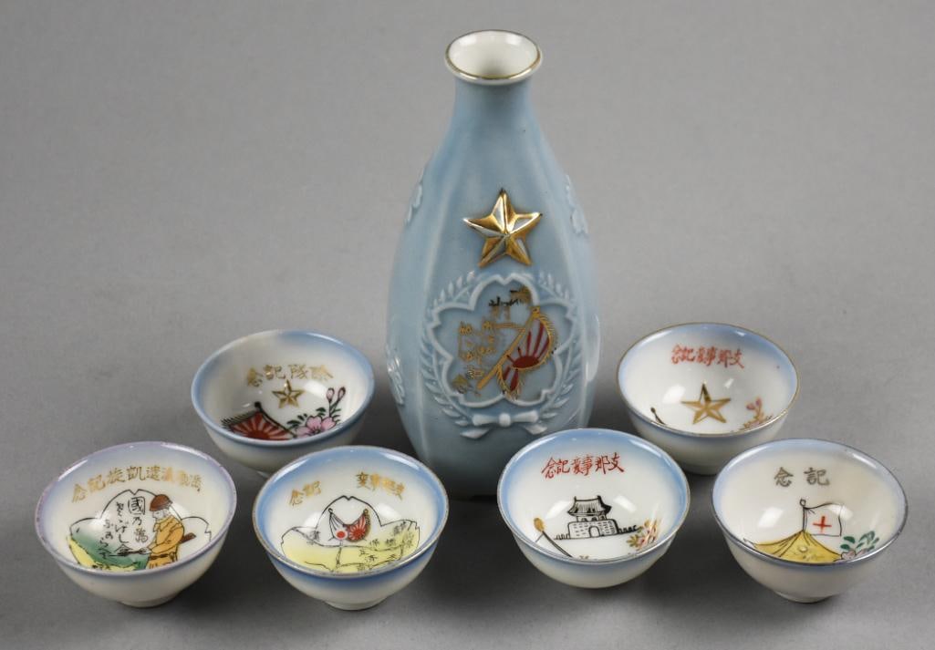 Early Japanese Military Commemorative Saki Set: This spectacular set is an early Japanese military saki set that includes a bottle and six cups. The embossed bottle with hand painted horses and flag and signature on bottom. Each cup with a differen