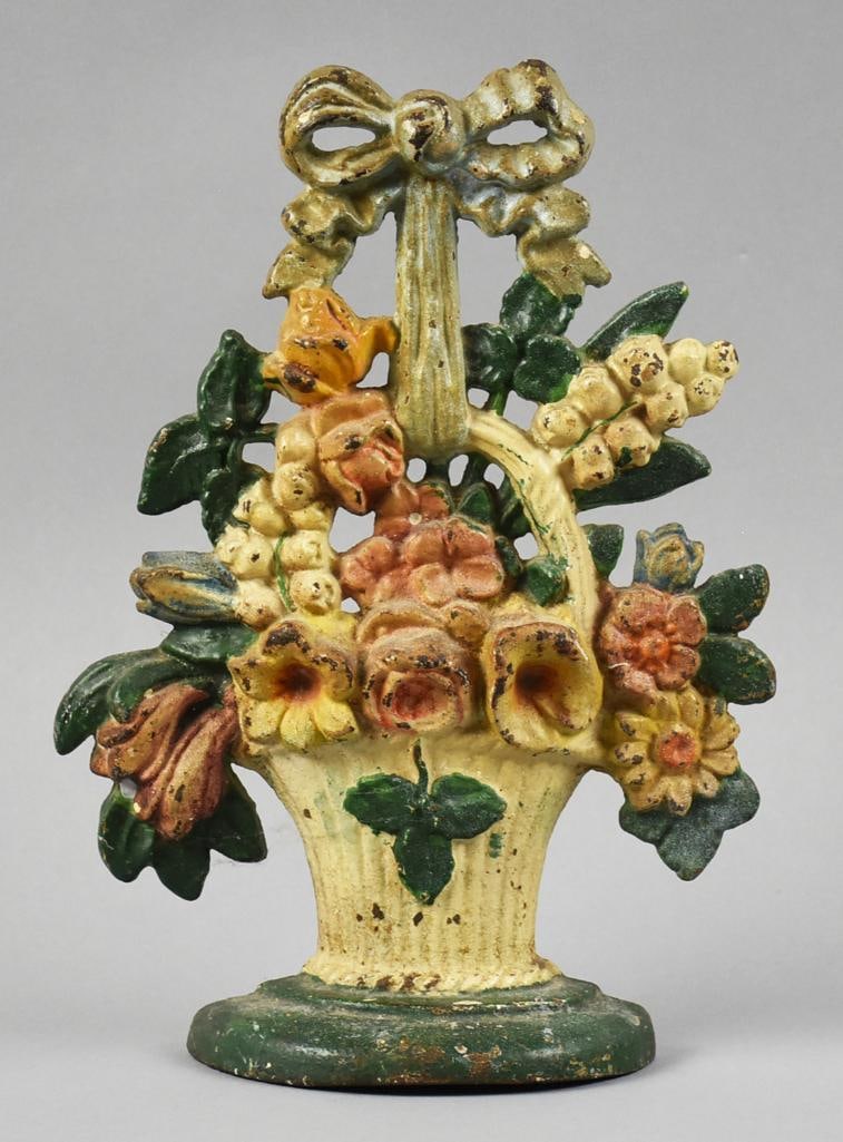 c1925 Hubley Flower Basket Cast Iron Door Stop #34: This wonderful piece is a cast iron door stop from Hubley. Flower basket with ribbon, flower variety and polychrome painted in neutral yellows and oranges with green leaves. Number on back is 34, no o
