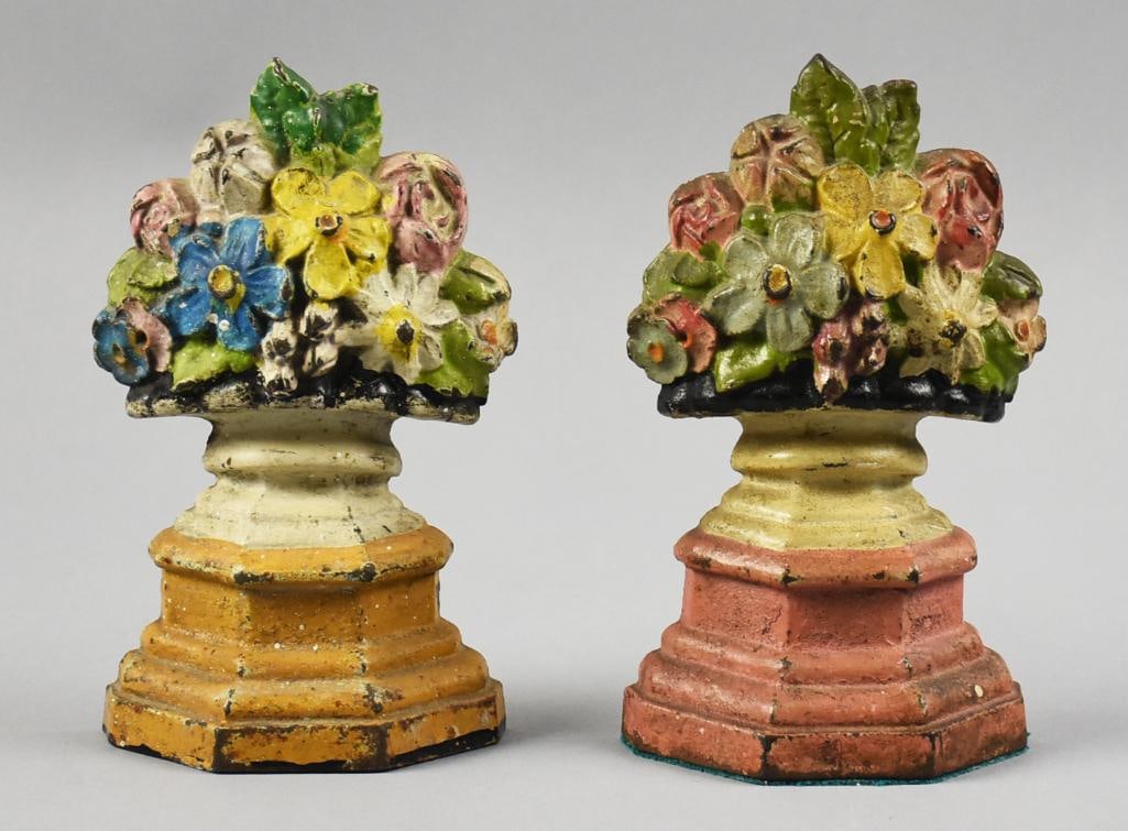 Pair c1925 Hubley Flower Urn Cast Iron Door Stops: This is a wonderful pair of cast iron door stops from Hubley. They are both in the form of flower urns, each with bouquets of flowers. They are painted in polychrome, one orange base, one pink. One al