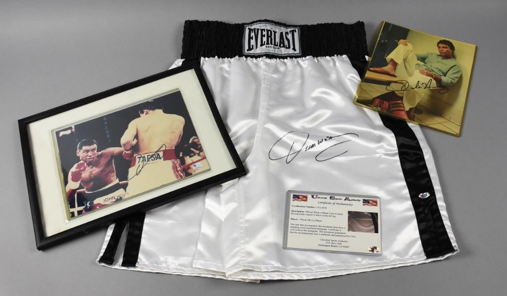 Oscar De La Hoya Signed Photo & Trunks, COAs, Stickers: Nice pieces of Oscar De La Hoya memorabilia that includes a signed 8 x 10 photograph with validation sticker from Global Authentics number GV242240. The trunks are also signed and include a COA from