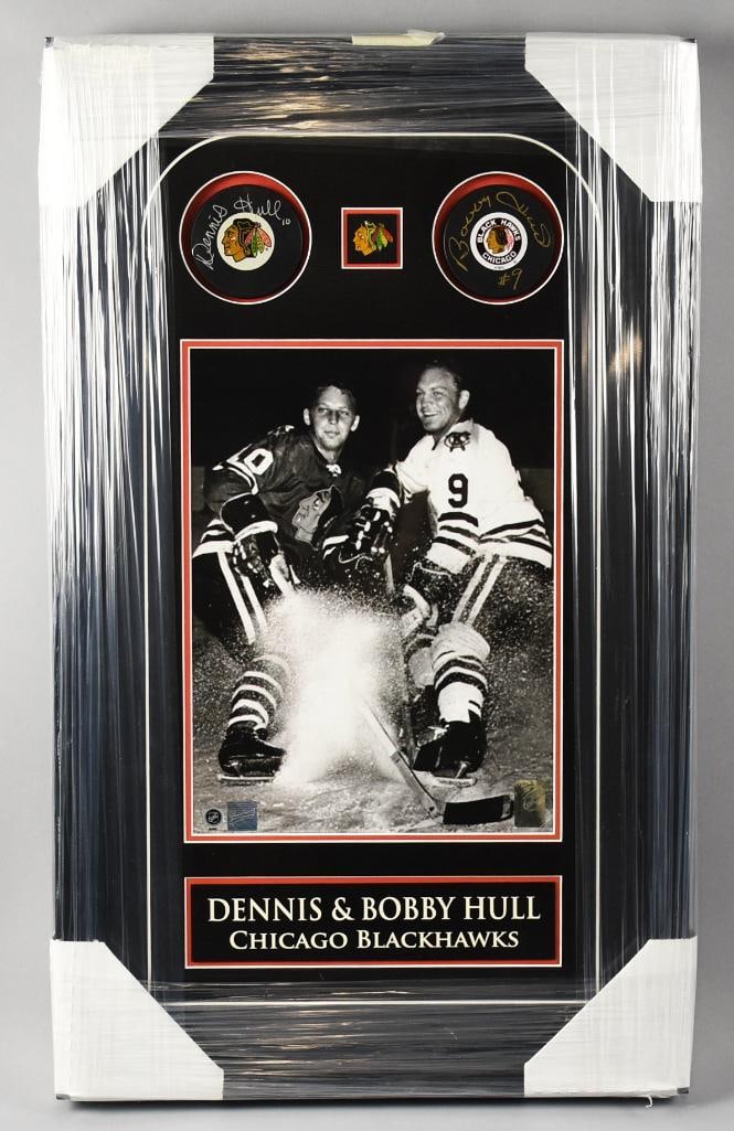 Dennis & Bobby Hull Chicago Blackhawks Signed Pucks, Hologram: Dennis & Bobby Hull Chicago Blackhawks Dual-Signed Puck Display This is a framed Chicago Blackhawks memorabilia display featuring two signed pucks, a black-and-white photo of brothers Dennis Hull #10