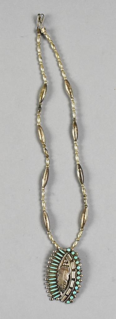 Libert & Carol Peketewa Zuni Turquoise Sterling Pendant Necklace: Beautiful sterling and turquoise pendant necklace from Zuni jewelry artists Libert & Carol Peketewa. Oval shape with center leaf surrounded by inlay of round and oval turquoise. Hangs on a sterling
