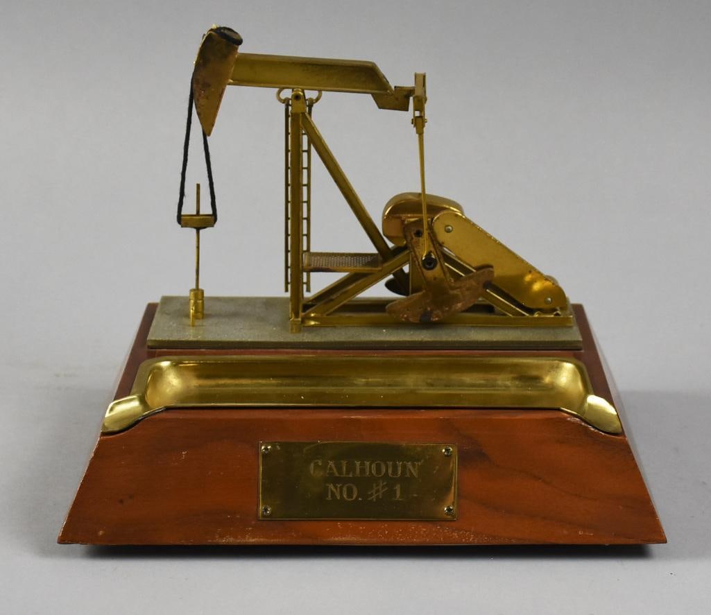 Vintage Calhoun #1 Oil Field Pump Jack Brass Desk Model: Very cool vintage pump jack for the oilfields. It is called a Calhoun #1 and brass. Desktop model with what appears to be a pen tray in front. It is mounted to a tall wooden base with a brass plate at