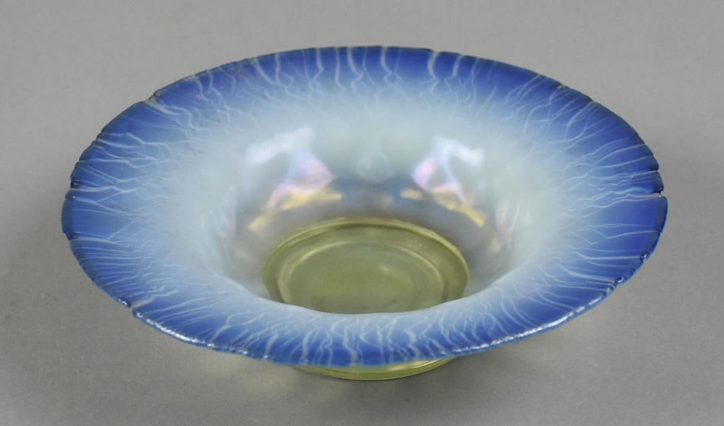 Tiffany Blue Favrile Glass Signed Scallop Rim Bowl: This is a stunning piece of art glass from Louis Comfort Tiffany. It is from the Favrile line and is blue iridescent with stretched rim. Base with subtle yellow gold. Base is marked LCT Favrile?and B 