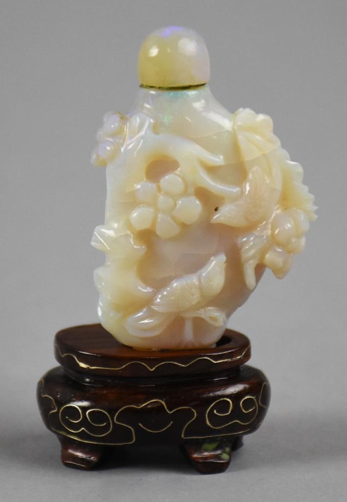 Chinese Export Hand Carved Opal Snuff Bottle: This is a gorgeous Chinese export. Snuff bottle appears hand carved from opal with a gorgeous floral and fish motif with the original cap. It comes on a beautifully decorated stand that appears rosewo
