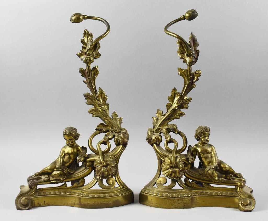 Antique Louis XV Rococo Cherub & Leaf Bronze Andirons: Wonderful pair of andirons that appear gilt bronze. They are Louis XV rococo style with a reclining cherub in front of an acanthus leaf vine. The are of France origin and measure approx. 19" x 11".