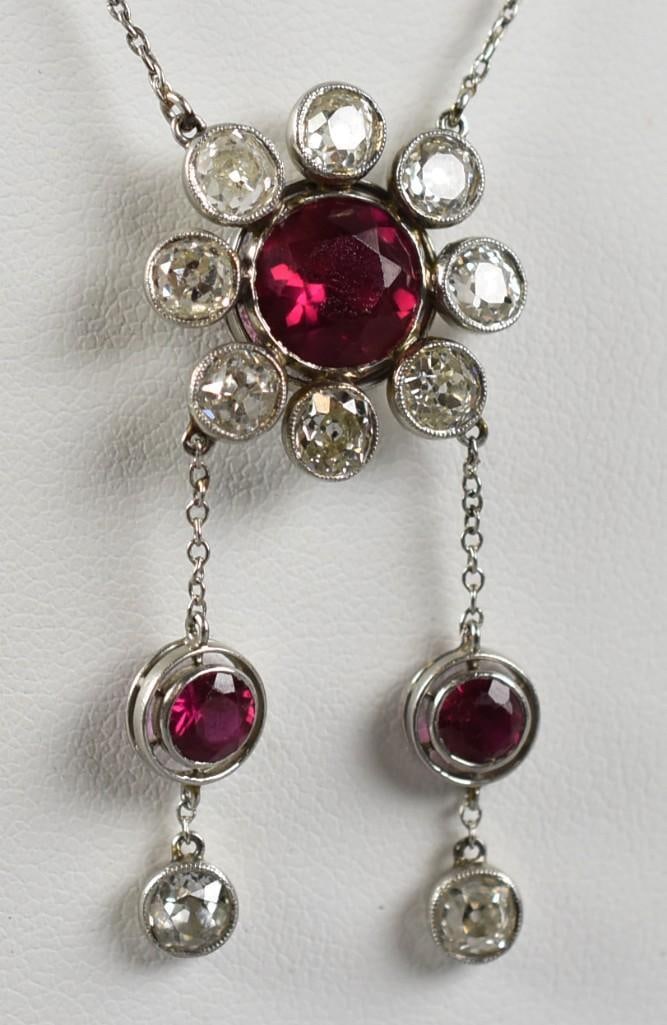 14K White Gold, Ruby & Diamond Flower Necklace: This stunning necklace appears to be a one of a kind creation. Chain and clasp are white gold. The flower pendant with two chains dangling, both with ruby and diamonds. The larger center ruby is