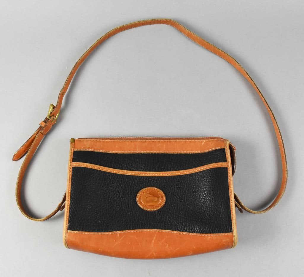 Dooney & Bourke Leather Cross Body Bag USA Made: Nice and classic is this cross body bag from Dooney & Bourke. All weather leather in black with tan accents and strap. It is USA made with label inside and medallion on front.