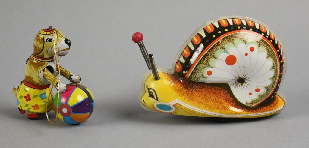 Vintage Tin Litho Wind Up & Ornament: Cute pair of vintage tin litho toys. They include a dog wearing a skirt pushing a ball from ZZ Germany and is an ornament. The snail is attributed to Woniu?made in China in the 1960s.