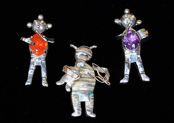 3 Sterling Native American Figurines: Total of 3 sterling silver figurines. 2 drum players, 1 with purple stone & 1 with orange stone. 1 figurine is holding a child and a tool. All marked "Sterling" with an "M" on the backside of the figu