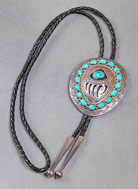 Native American Sterling & Turquoise Bolo: Beautiful bolo tie bezel set with 17 individual turquoise stones, leather cord, bear claw design in center, marked "W.M. Sterling", 2 1/2" x 3". 18" in length. Weight = 2.43 oz. 18% buyers premium.