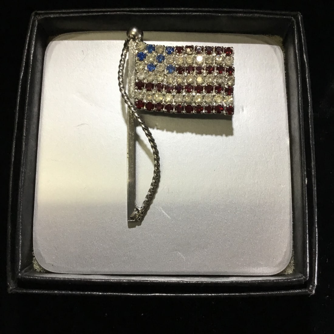 VINTAGE AMERICAN FLAG BROOCH USA PATRIOTIC RED WHIT & BLUE PIN: Show off your patriotic side with this vintage American flag brooch. The brooch features a red, white, and blue color scheme with sparkling rhinestones. The brooch is made of silver-tone metal and has