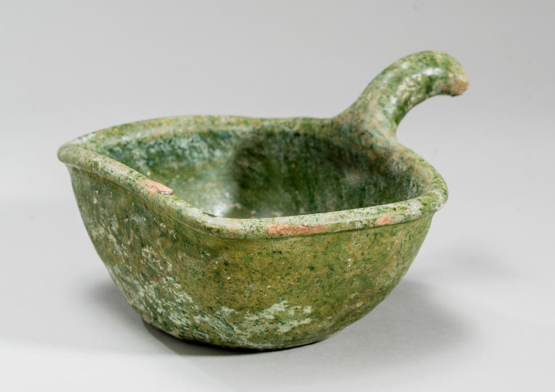 A VESSEL WITH HANDLE: A VESSEL WITH HANDLE Glazed ceramic China, Han dynasty (206 BC-220 AD) An interesting, if simple, find! Its sober form is clear. A deep bowl with slightly flared sides and lip. There is a handle on on