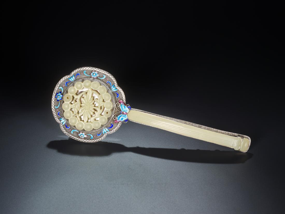 AN ENAMELED SILVER AND JADE HAND MIRROR, LATE QING: AN ENAMELED SILVER AND JADE HAND MIRROR, LATE QING DYNASTY Silver, enamel and pale celadon jade China, late Qing Dynasty A Ruyi scepter shaped mirror in a silver frame, enameled with butterflies and f