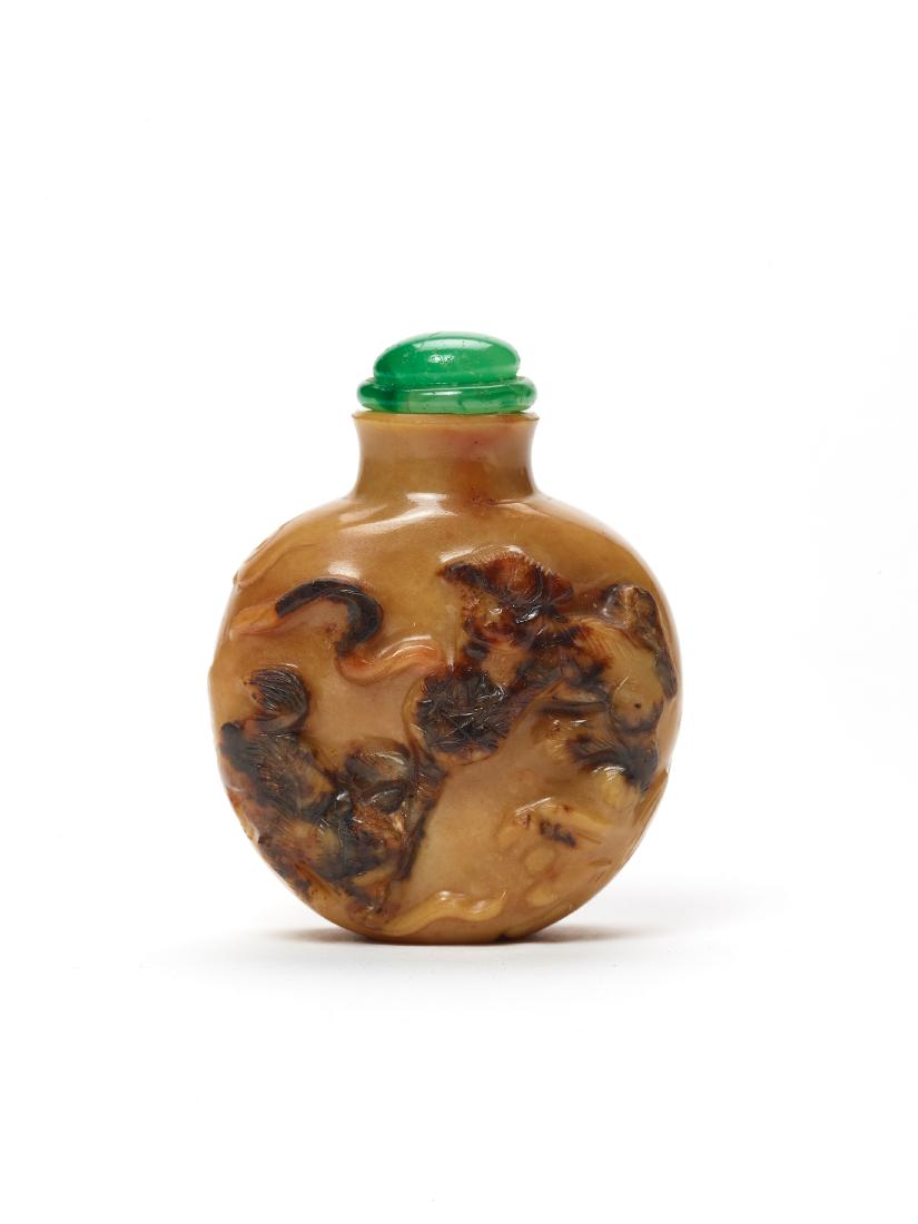 A CARVED 'BUDDHIST LIONS' AGATE SNUFF BOTTLE, MODERN: A CARVED ‘BUDDHIST LIONS’ AGATE SNUFF BOTTLE, MODERN Agate, carved in high relief, the mineral opaque and of caramel color with dark-brown inclusions China, later 20th century Carved on on