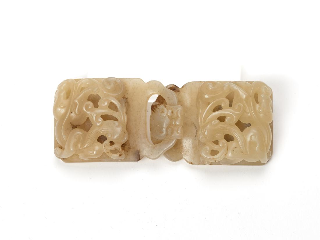 A CELADON JADE BELT BUCKLE WITH CHILONG AND LINGZHI: A CELADON JADE BELT BUCKLE WITH CHILONG AND LINGZHI Celadon jade with russet inclusions, smooth surface polish China, 19th / 20th century This well executed two-part jade belt buckle is carved and pie