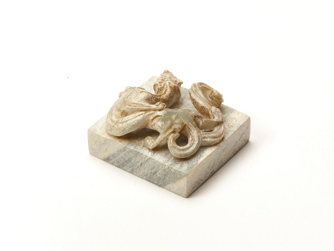 A HAN DYNASTY STYLE JADE SEAL WITH A CHILONG: A HAN DYNASTY STYLE JADE SEAL WITH A CHILONG Creme jade, opaque, hand carved China This creme jade seal has an elegantly winding chilong on top with a thin neck and a bifurcated tail. Dimensions: SIZE