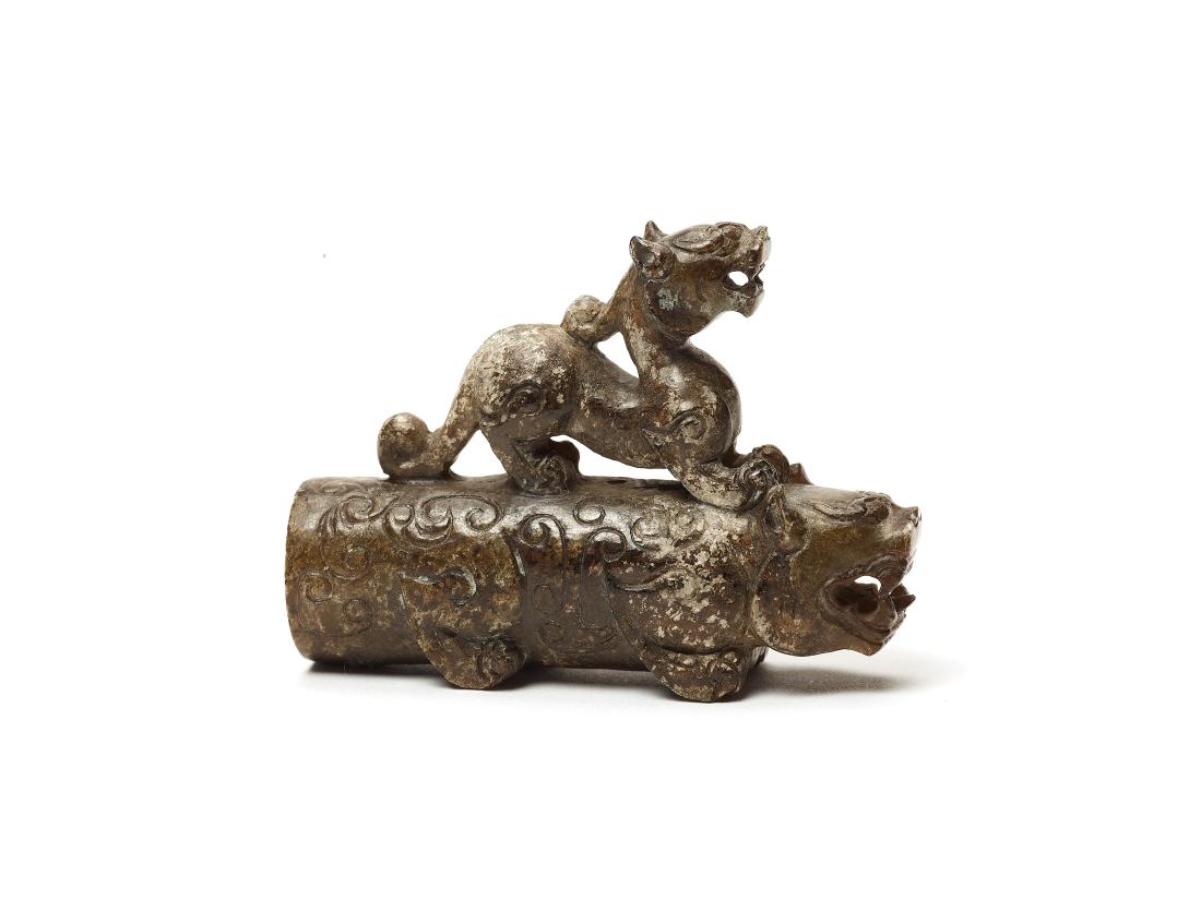 A HAN DYNASTY STYLE FIGURE OF TWO TIGERS: A HAN DYNASTY STYLE FIGURE OF TWO TIGERS Brown jade, opaque, hand carved China This brown jade figure shows a tiger with a second animal, presumably also a tiger but with a more mythical appearance, o